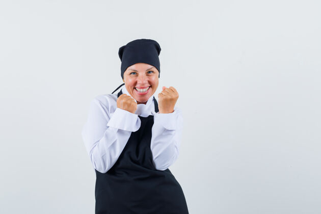漂亮身着黑色厨师制服的金发女人展示着成功的姿态 看上去很开心正面图自然制服可爱