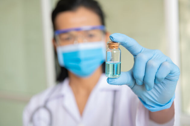 治疗女医生肩上带着听诊器 手持注射器和covid-19疫苗医生手里拿着冠状病毒疫苗的概念蓝色疫苗罐疫苗对抗冠状病毒的概念医院医学液体