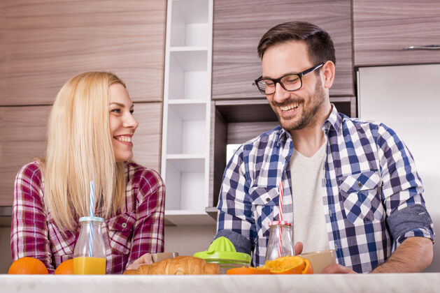 爱年轻幸福的夫妇在厨房里喝着新鲜的橙汁家庭成熟女性