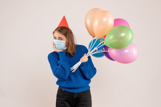 面具戴着白色面具手持彩色气球的年轻女性举行气球庆祝