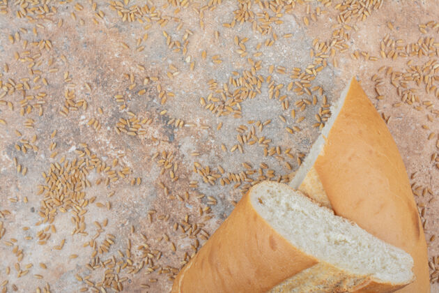 食品半切小麦面包和大麦在大理石表面一半新鲜大麦