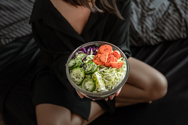 自然一个大碗的特写镜头 女人手里拿着新鲜准备的蔬菜沙拉坐着生的沙拉
