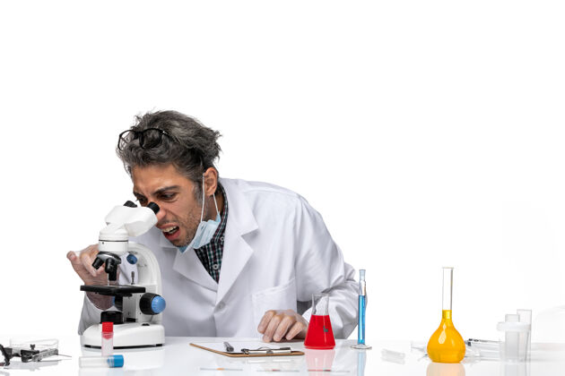 视图穿着白色医疗服的中年科学家使用显微镜的正视图实验室外套实验使用