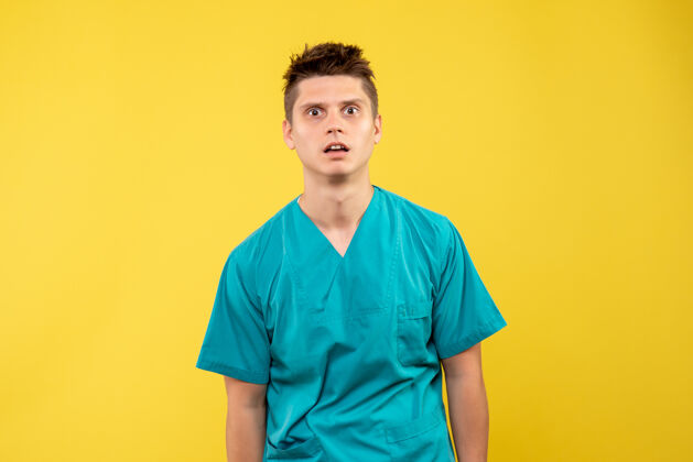 肖像正面图黄色背景上穿着医疗服的年轻男医生年轻男性医生背景医学