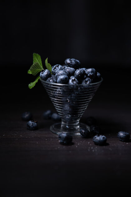 冷在一堵黑墙上的玻璃里垂直拍摄蓝莓饮食多汁水果