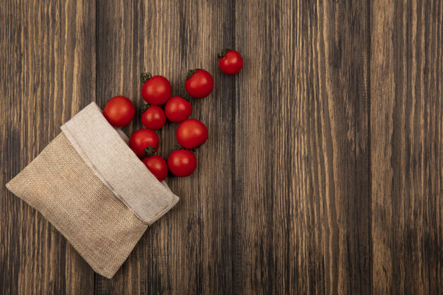 顶部有机红色西红柿从粗麻布袋里掉出来的俯视图 在有复印空间的木墙上西红柿有机景观