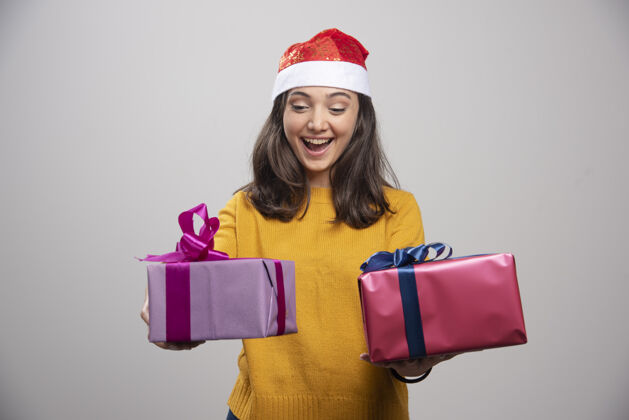 模型戴着圣诞帽的年轻女子看着她的箱子乐趣女士快乐