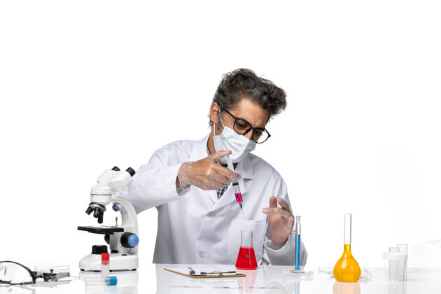 医学正面图身着白色医疗服的中年科学家用红色溶液填充注射剂实验室化学科学