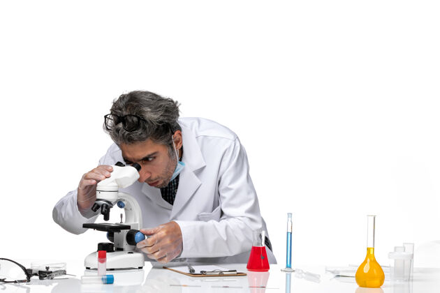 人前视图中年科学家穿着特殊的白色西装使用显微镜外套工作医学