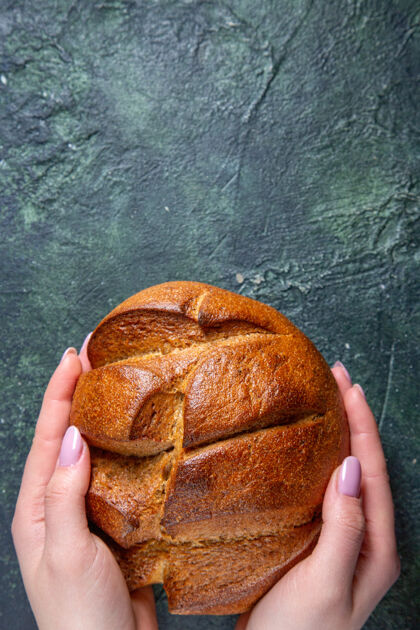 馒头顶视图新鲜黑面包与女性的手在黑暗的桌子上面包顶部食物