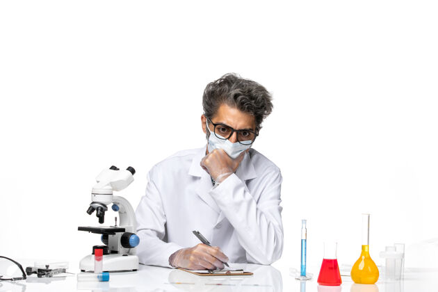 人正面图中年科学家穿着特别套装坐着写笔记医学实验前面