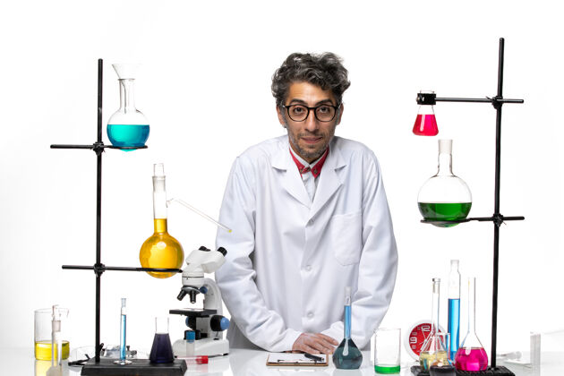 医疗正面图穿着白色医疗服的男科学家站在桌子前拿着解决方案解决方案人化学