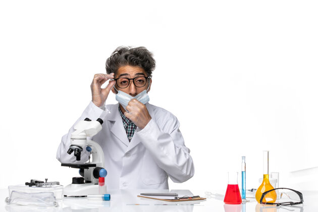 医学正面图身着特殊套装的中年科学家围坐在桌子旁 拿着显微镜和溶液实验室男化学