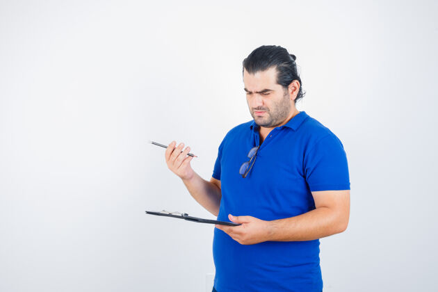 现代一幅中年男子穿着马球衫拿着铅笔 一边看着剪贴板 一边沉思的前视图的画像肖像单身男性