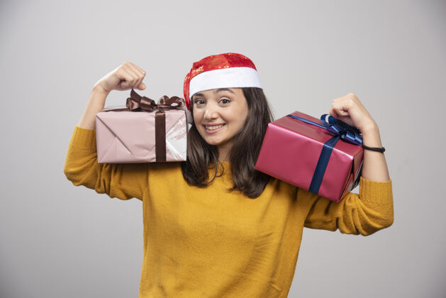 黑发戴圣诞帽的微笑女人展示礼品盒漂亮表情礼品盒