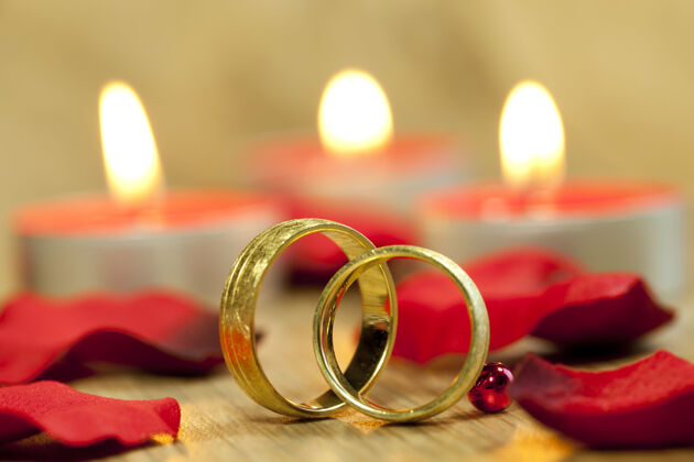戒指婚礼戒指的特写镜头 背景是美丽的红玫瑰和蜡烛钻石自然闪亮