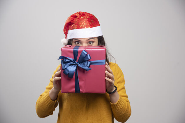 圣诞老人戴圣诞帽的快乐女人躲在礼品盒后面女人圣诞节模型
