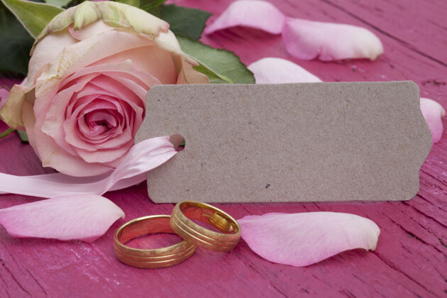 闪亮订婚戒指特写镜头 一个标签和美丽的粉红玫瑰在桌上自然婚礼戒指