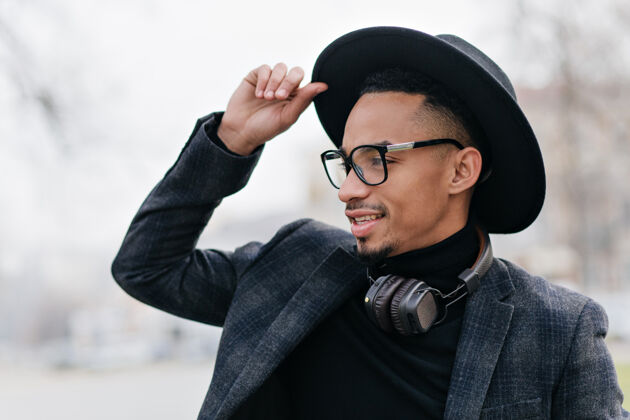 音乐留着短发的非洲男人用梦幻般的表情遥望远方黑人在城市里享受周末的户外写真娱乐耳机休闲