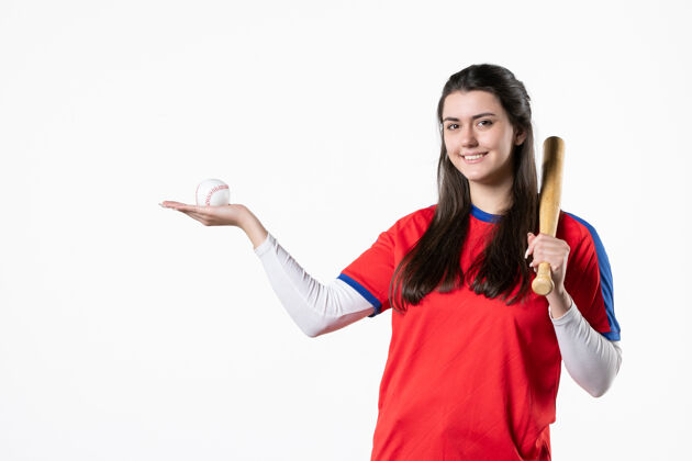 微笑前视图：带球棒和球的女棒球运动员视图人前面