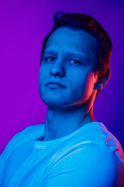 表情在五彩霓虹灯下 紫蓝色背景上的白种人肖像男人霓虹灯复古