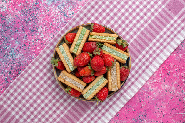 新鲜美味的华夫饼干的顶视图 粉色表面有新鲜的红色草莓多汁的顶视图生的
