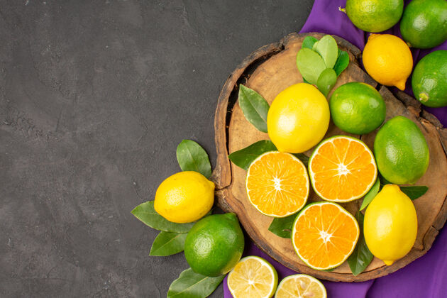多汁在一张深色的桌子上俯瞰新鲜的酸柠檬 柑橘和酸橙水果柠檬健康柑橘