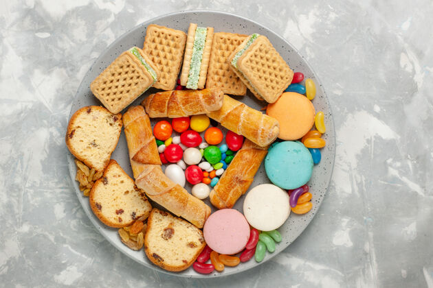 生的白色桌子上美味的华夫饼 麦卡龙蛋糕片和糖果的俯视图切片食物麦卡龙