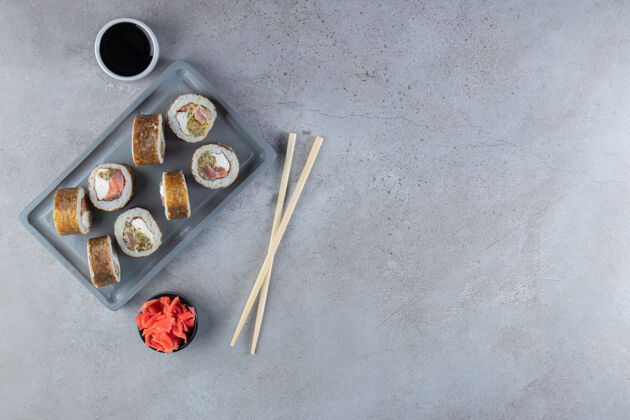 菜肴美味的寿司卷和金枪鱼放在深色盘子里鱼海藻午餐