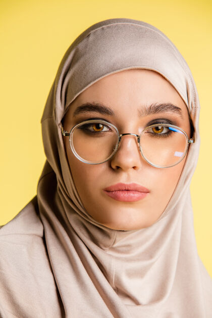 围巾美丽的年轻阿拉伯妇女在时尚的头巾隔离在黄色背景与空间服装化妆品欢乐