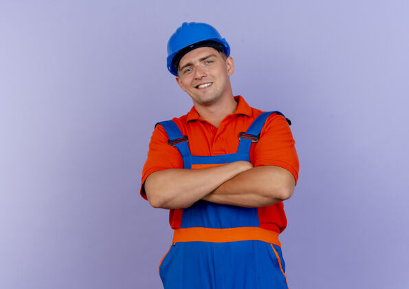 建筑工人高兴的年轻男子建设者身穿制服和安全帽交叉手上紫色请十字架年轻