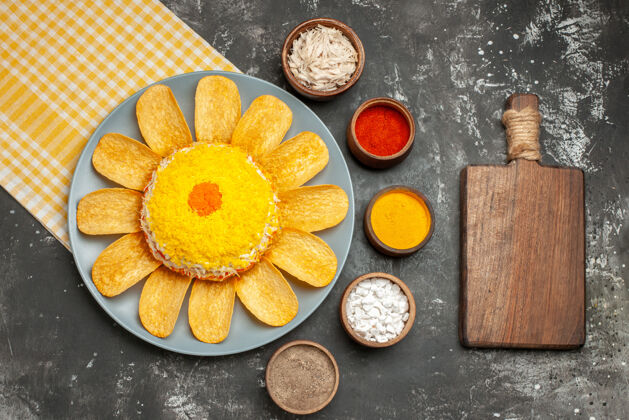 早餐沙拉的俯视图在左边 黄色的餐巾在它下面 药草砧板在深灰色的桌子上食物新鲜健康