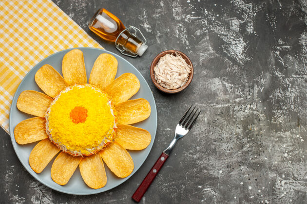 奶酪沙拉的俯视图在左边 黄色餐巾在下面 奶酪叉油瓶在深灰色的桌子上餐桌早餐叉子