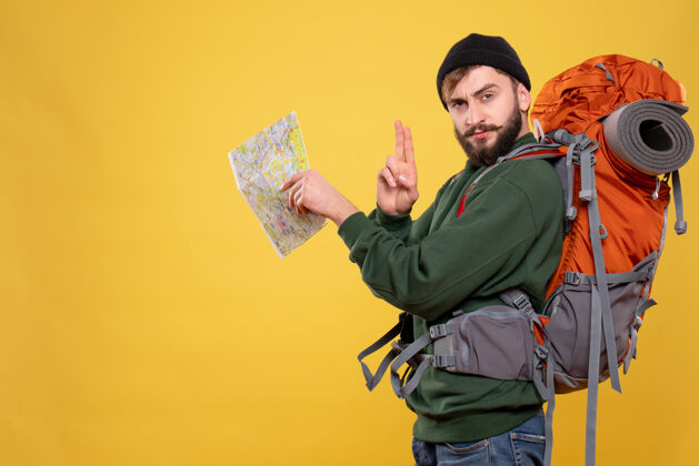 地图旅行概念与自信的年轻人与背包和持有黄色地图旅行成人专业