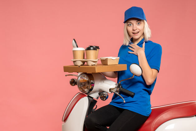 人正面图骑自行车的女快递员 咖啡杯是粉红色的杯子专业蓝色