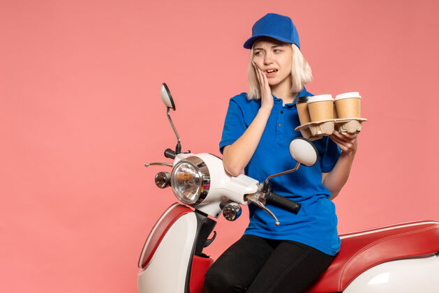 工作前视图骑在自行车上的女信使与咖啡杯上的粉红色身体女快递咖啡