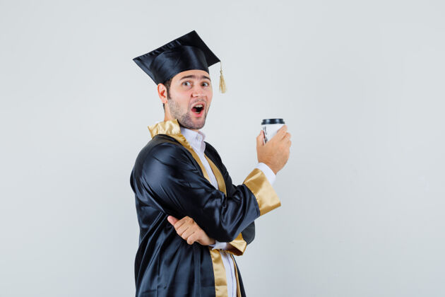 衬衫年轻的男学生穿着毕业制服 手里拿着一杯咖啡 看上去很开心正面图男人制服自信