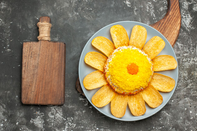 右边沙拉的顶视图在盘子架的右侧 在深灰色的背景上 切菜板在侧面深色甜橙柠檬