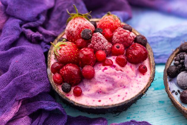 蔓越莓特写镜头的水果奶昔顶部冷冻草莓 红莓在椰子碗新鲜配料草莓