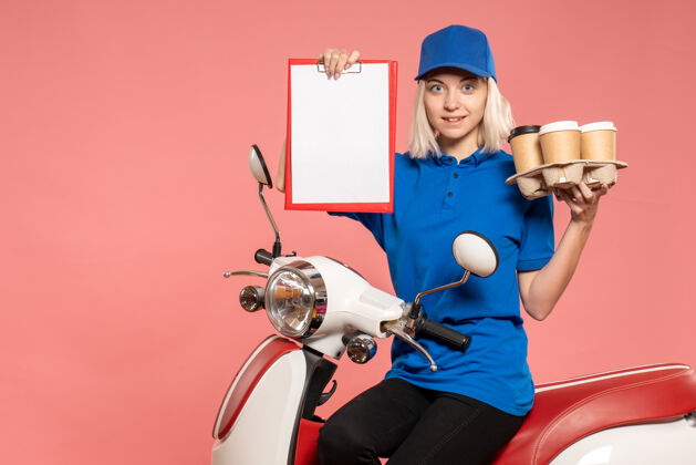 服务正面图骑自行车的女快递员 咖啡杯是粉红色的咖啡工作人