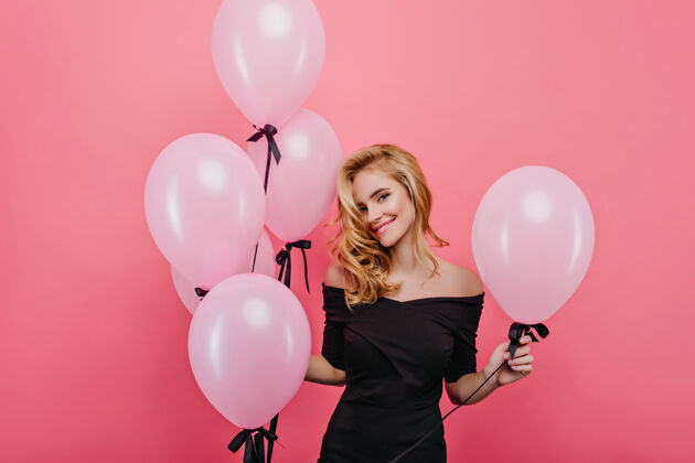 气球梦幻般的白人女子 可爱的脸庞 拿着气球在粉红色的墙上摆姿势优雅的金发女模特在派对上庆祝生日女人表情庆祝