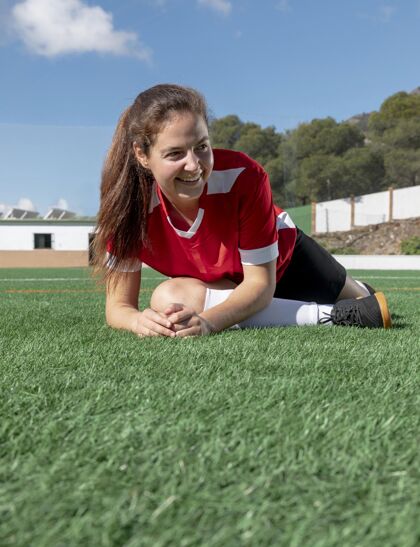 垂直快乐的女人在球场上伸展腿女子练习球员