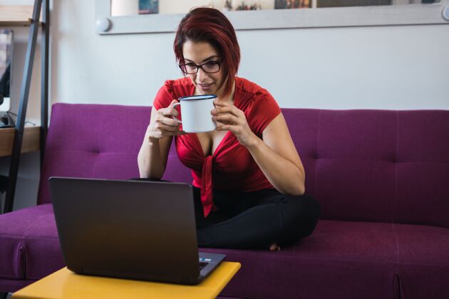 眼镜中年女性手拿杯子坐着用笔记本电脑交流工作肖像女人