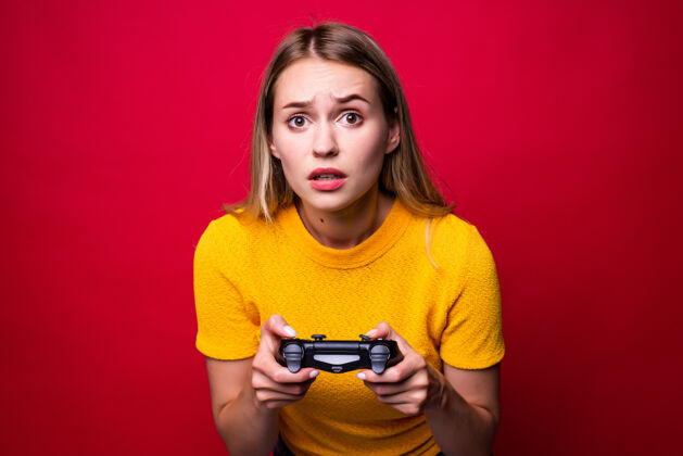 积极年轻的金发女游戏玩家使用游戏板玩视频游戏隔离过红墙西班牙人手控制