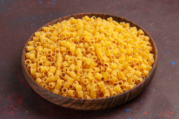 农产品前视图黄色意大利面食生小形成在黑暗的桌子上谷物少量膳食