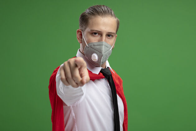 手势自信的年轻超级英雄 戴着医用面罩 打着领带 在绿色背景上显示你的孤立姿态男人年轻医疗