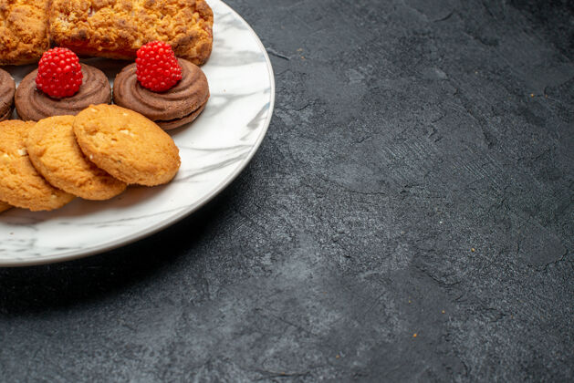 派在灰色桌子上的盘子里可以看到饼干和蛋糕浆果甜点饼干