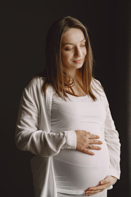 肚子孕妇站着摸她的肚子年轻成人父母