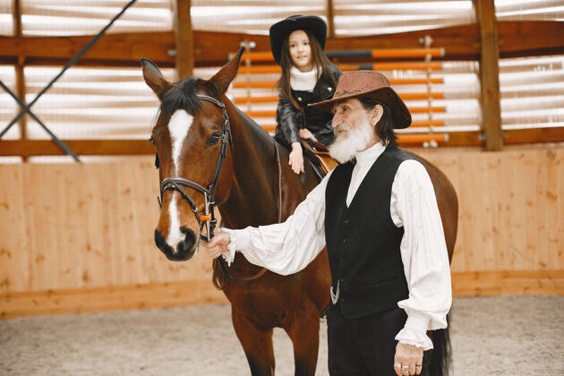 人戴头盔的女孩学骑马教练教小女孩老帽子夏天