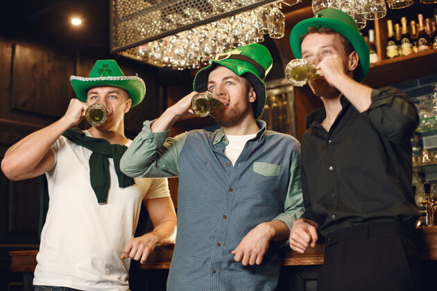 杯子戴绿帽子的男人朋友们庆祝圣帕特里克节在酒吧庆祝男性酒精团体